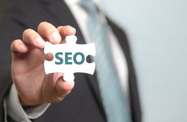 Businessmann hält SEO-Puzzle in Hand