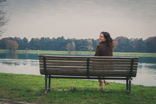 Beautiful young woman sitting on a bench in a city park