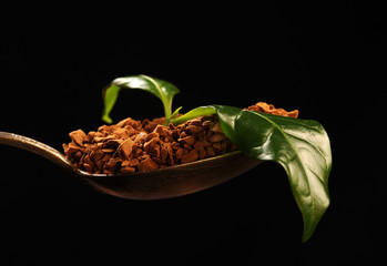 Obraz premium Kawa instant na łyżeczce z liściem kawowca