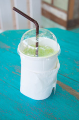 take-home cup of ice green tea on wooden table