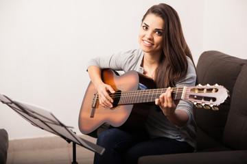 Cute girl playing guitar at home