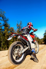 Fast moving motocross rider on dirt road.