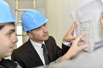 Supervisor with construction worker checking blueprint