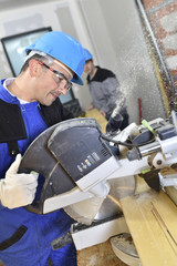 Closeup of carpenter cutting wood with electric saw