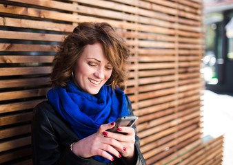 Smiling young woman using mobile smartphone on the street