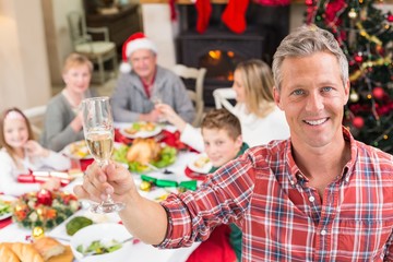 Smiling father toasting at camera in front of his family