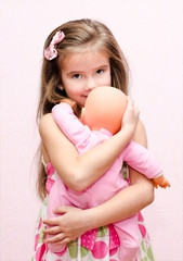 Cute little girl holding and embracing her doll