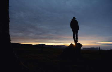 man standing on hill in black forest at sunset