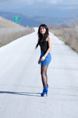 Woman in a blue skirt and black stockings on the open road