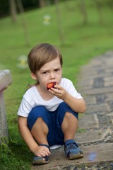 Little boy eating plum