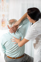Fototapeta premium Chiropractic: Chiropractor examining senior man at office
