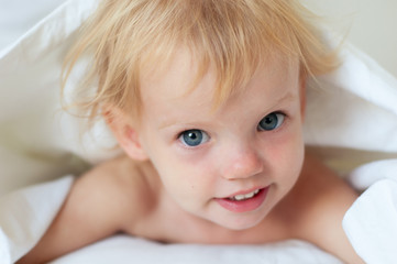 Adorable little girl in white bed