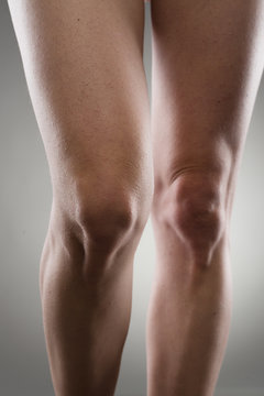 Healthy female legs over grey. Knee joint care concept.
