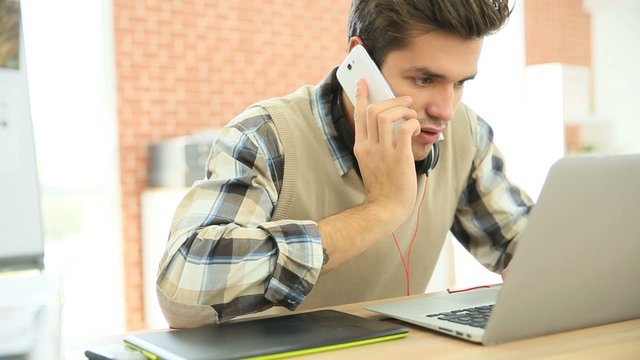 Young man in office answering phonecall