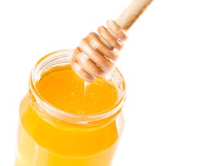 honey jar on white background with wooden honey dipper on top
