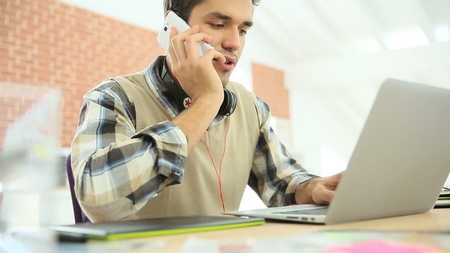 Young man in office answering phonecall