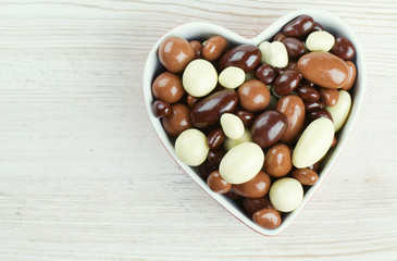 chocolate covered nuts and raisins in a heart-shaped bowl on woo