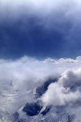 Snowy mountains in clouds and sunlight sky