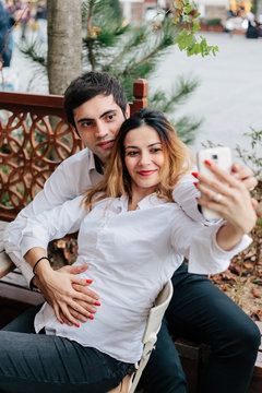 Young couple waiting baby, takes a Selfie in a bar