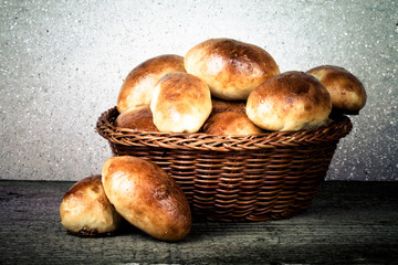 pies with meat or cabbage in a wicker basket on a wooden backgro