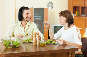 brunette woman with man eating veggie salad at home