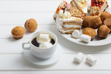 coffee with marshmallow and cake on white wooden background
