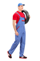 Mechanic carrying a tire and walking