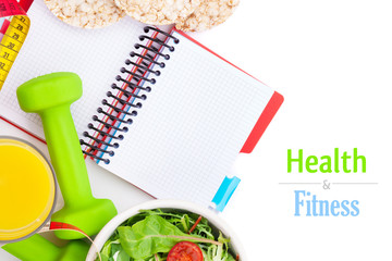 Dumbells, tape measure, healthy food and notepad for copy space.