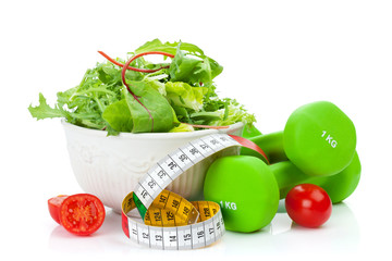 Two green dumbells, tape measure and healthy food. Fitness and h