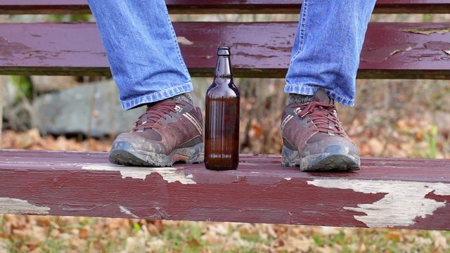Beer bottle near man's dirty boots