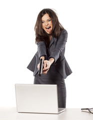 angry businesswoman wants to shoot at her laptop with a gun