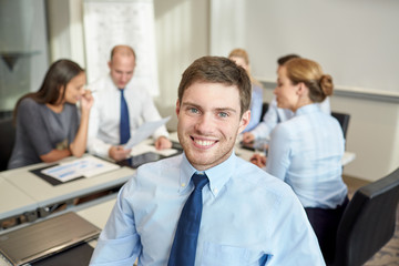 group of smiling businesspeople meeting in office