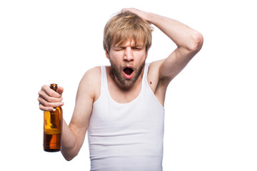 Young man with hangover holding beer bottle