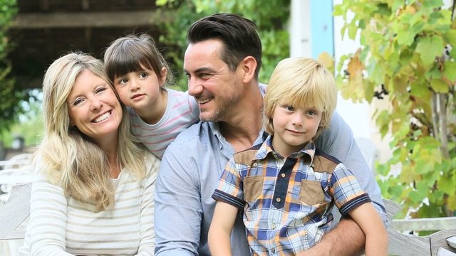 Family of four sitting in front of house