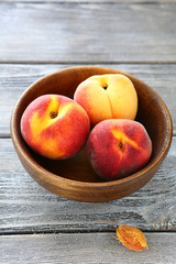 fragrant and fresh peaches in wooden bowl