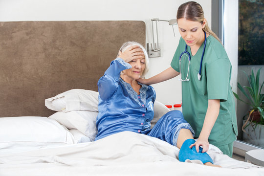 Caretaker Using Hot Water Bag On Senior Woman