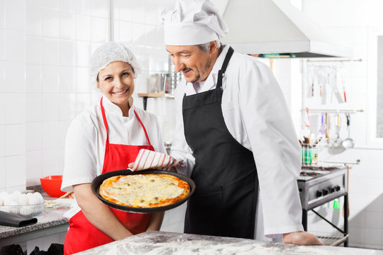 Happy Chef Standing By Colleague Holding Pizza Pan