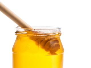 honey jar on white background with wooden honey dipper inside