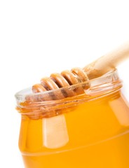 honey jar on white background with wooden honey dipper inside