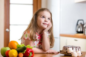 Obraz na płótnie Canvas kid choosing between healthy vegetables and tasty sweets
