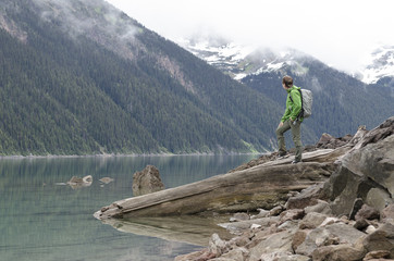 Man standing on a cliff looking at mountain lake