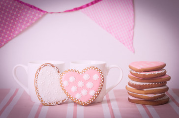 two cups and heart cookies on pink