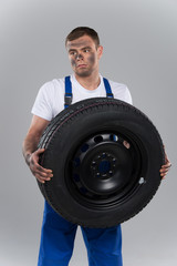 pensive man holding tire on grey background.