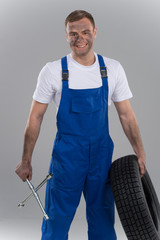 young mechanic holding wrench and tire.