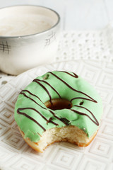 Bitten delicious donut on plate on wooden table close-up