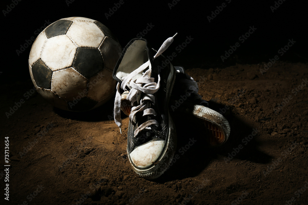 Poster Soccer ball on ground on dark background