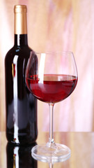 Red wine glass and bottle of wine on bright background