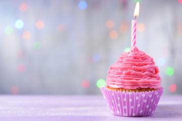 Delicious birthday cupcake on table on light background