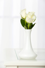 Beautiful bouquet of flowers in vase on window background