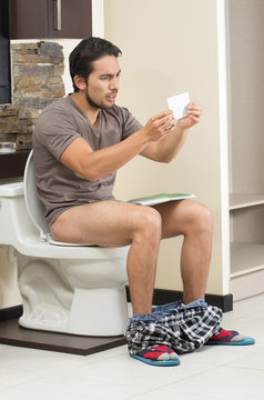 worried man sitting on the toilet running out of paper